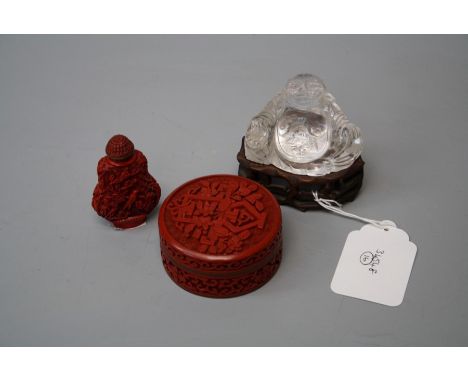 A 20th century rock crystal figure of a corpulent Buddha seated on a faux rootwood socle 8cm wideTogether with faux cinnabar 