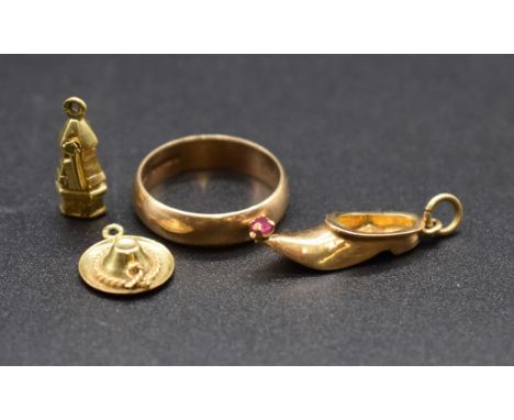 A 9ct gold wedding band, 2.9g; together with a yellow metal slipper charm set ruby, 24mm; and two yellow metal charms. (4) 