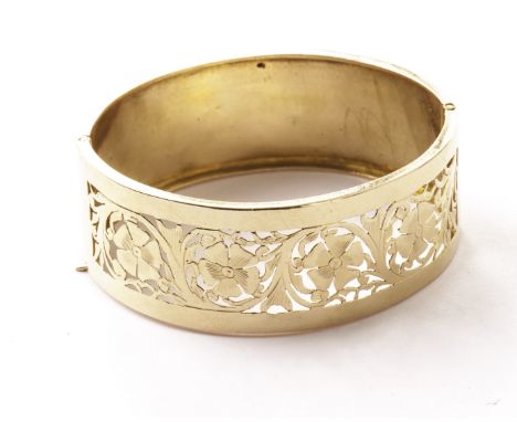 A Middle Eastern yellow metal cuff bangle, one half with pierced floral designs, the other half with engraved flower and leav