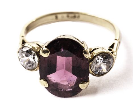 A gold and three stone ring, having a large purple and two transluscent paste stones in yellow gold mount