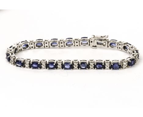 A pretty sapphire and diamond tennis style bracelet, having oval cut blue stones in claw mounts alternately set with a pair o