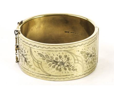 A modern silver gilt bangle, having engraved foliage to one half, the other half plain