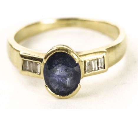 A modern Ceylon sapphire and diamond ring, the oval cut blue stone in collet mount and having three baguette cuts channel set