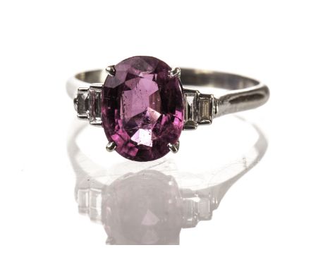 A modern pink tourmaline and diamond dress ring, the white 18ct gold mount supporting an oval cut pink stone having two bague