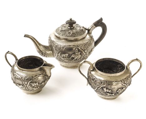 An Indian white metal three piece tea set, comprising teapot, milk jug and sugar basin, all with ornate embossed designs of a