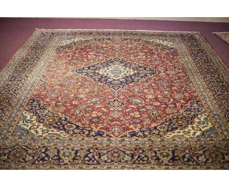 KASHAN BORDERED CARPET
decorated with a large central medallion on a flower filled field on a blue ground, 395cm long, 290cm 