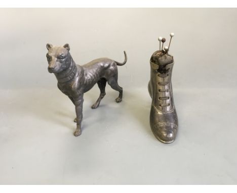 A pewter pin cushion in the form of a boot, with a dog figurine.