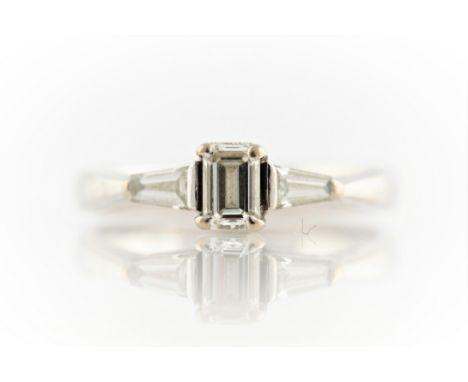 A three stone diamond ring, set with a principle rectangular cut diamond, flanked to either side with a tapered baguette cut 