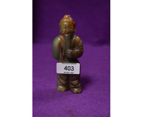 A Tibetan style figure of a monk or similar hand carved in a brown and pale green nephrite jade stone