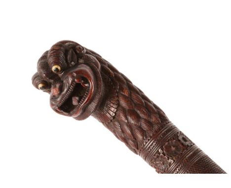 A BURMESE CARVED HARDWOOD WALKING STICK with 'Yuli' head handle and spiral animal motif, 98cm long