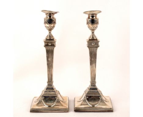 A pair of George III silver candlesticks, maker indistinct, London 1784, of Neoclassical form with swagged sconces, square fl