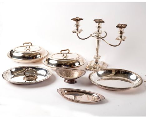 A silver plated three-branch candelabra, a pair of plated entree dishes, another entree dish, a plated bonbon dish and a boat