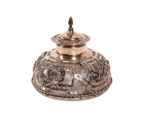 An Edwardian silver inkwell, William Comyns, London 1904, the hinged cover with cone finial, the sides with pierced and wreat