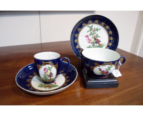 Two Worcester saucers, a coffee cup and a teacup, circa 1770, painted birds in a single cartouche on a wet blue ground/Proven