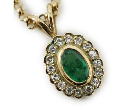 A modern 9ct gold, emerald and diamond set oval cluster pendant, 16mm, on a 9ct gold chain, 44cm, gross weight 4.1 grams.