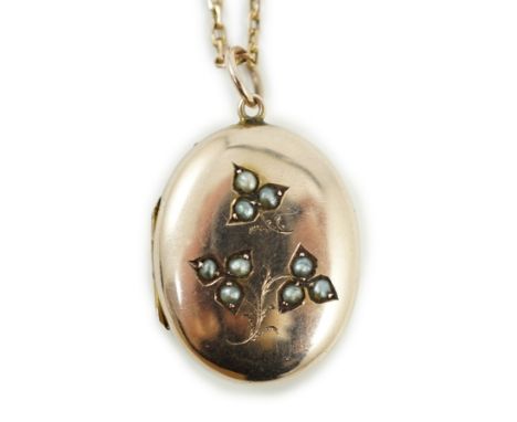 An Edwardian yellow metal and seed pearl set oval locket pendant, 25mm, on a 9ct chain, 47cm, gross weight 9.3 grams.