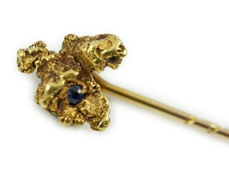 A late Victorian yellow metal and single stone sapphire set 'nugget' stick pin, 62mm, gross weight 3.2 grams.