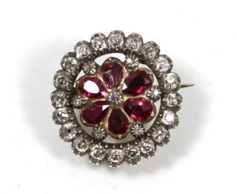 A ruby and diamond brooch, a central old cut diamond within a border of pear cut rubies and an outer circular frame of diamon
