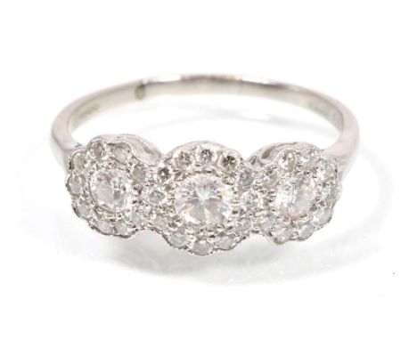 A platinum diamond triple cluster ring, three graduated round brilliant cut diamonds each within a border of diamonds, total 
