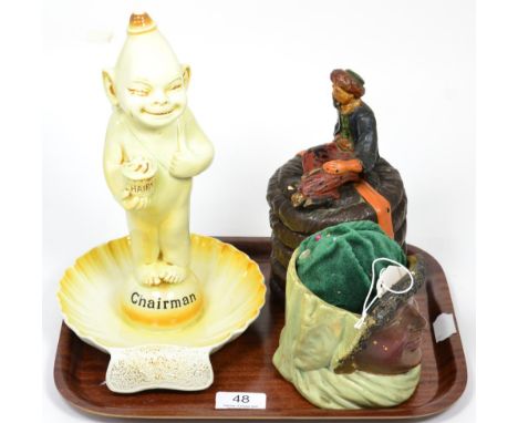 A Wilkinson novelty ashtray, 'The Chairman'; a tobacco jar and cover modelled as an Arab sitting on a basket; and another tob