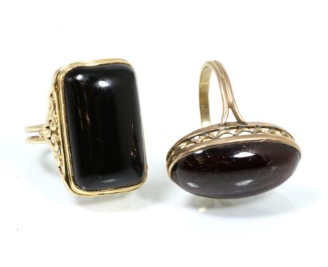 An onyx dress ring, with fancy scroll shoulders and split shank, finger size Q1/2, inscribed '14K', 12.2g and a garnet caboch