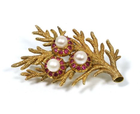 A cultured pearl and ruby floral brooch, three cultured pearls within ruby petal borders, to textured leaves, measures 5cm by