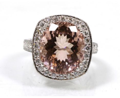 An 18 carat white gold morganite and diamond cluster ring, an oval cut morganite in a double claw setting, within a border of