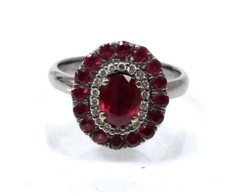 A ruby and diamond cluster ring, an oval cut ruby within a border of round brilliant cut diamonds and round cut rubies, total