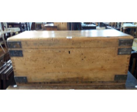 A 3' 3" heavy waxed pine and iron bound maritime transit trunk with flanking lugs for rope handles, set on drag rails