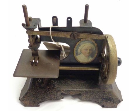 An early 20th Century Sotoy toy sewing machine with Martha Washington portrait to one side 