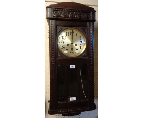 An early 20th Century oak framed wall clock with visible pendulum, bevelled arched glazed panels to door and eight day spring