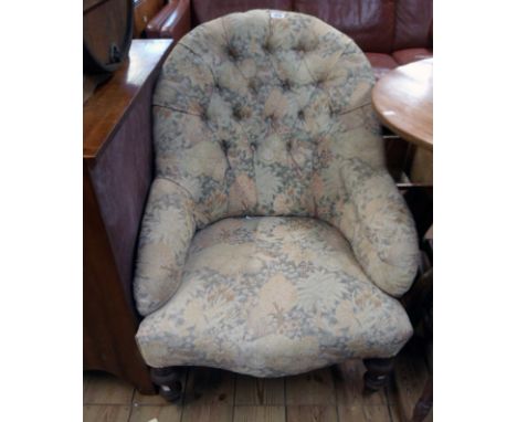 A Victorian parlour armchair upholstered in button back floral tapestry, set on turned front legs with white porcelain caster