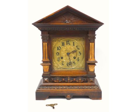 A late Victorian oak bracket clock of architectural form with pointed pediment, fluted pillars on bracket feet, the brass dia