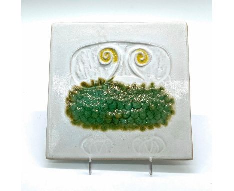 Ceramic tile with green, white, and yellow hand-painted glaze. Decorated with sunken relief of an owl. Stamped with '*1535' o