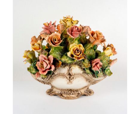 Large floral arrangement of colorful garden roses and leaves attached to a detailed cream colored planter. Made Italy backsta