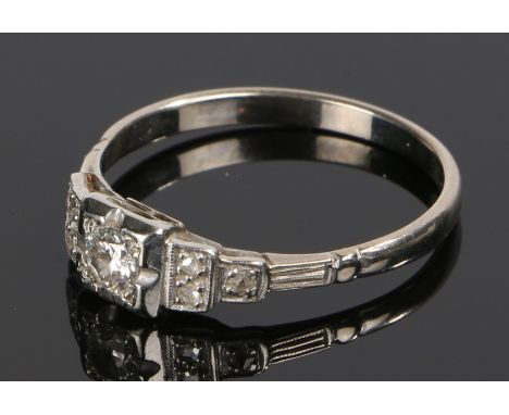 Diamond set ring, with a round cut diamond to the head and three diamonds to either shoulder on a white metal shank, ring siz