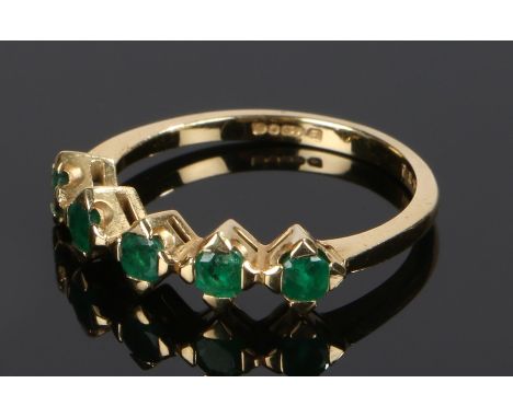 18 carat gold emerald set ring, with  row of five emeralds to the head, ring size M 1/2