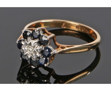 9 carat gold sapphire and diamond set ring,  the flower form design head set with sapphires surrounding a central diamond, ri