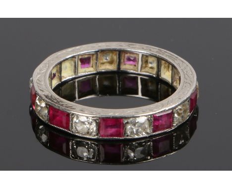 Ruby and diamond eternity ring, with a row of emerald cut rubies and round cut diamonds to the shank on white metal, ring siz