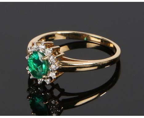 18 carat gold emerald and diamond set ring, with a central oval emerald and diamond surround, ring size O