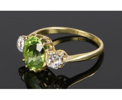 Peridot and diamond set ring, the central peridot at 2.26 carat with a diamond to either shoulder, ring size K
