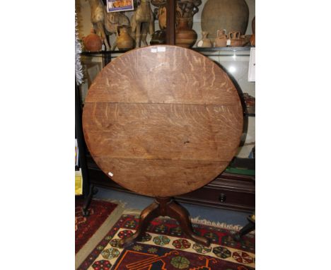 A George III oak tripod table, circular tilt top raised on a pedestal support