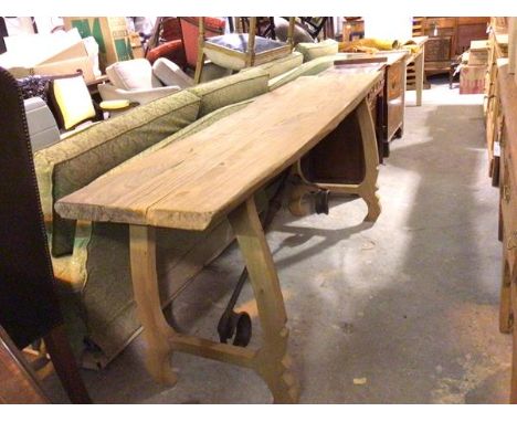 An oak Spanish style console table with planked shaped top raised on curved scroll supports with wrought iron stretcher (81cm