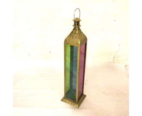 An Eastern brass embossed rectangular dome top candle lantern with coloured glass panelled sides, on pierced embossed stepped