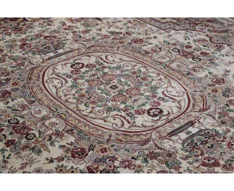 A Large Wool Carpet, the carpet has an overall floral motif, pink central design with green highlights set on a cream and bei