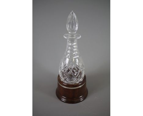 A Cut Crystal Decanter, supported on a polished oak stand with silver banded rib, London hallmark, dated 1989, mm Pierce Hart