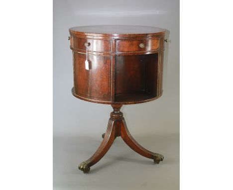 A Mahogany Revolving Drum Table; the table having six drawers, three being dummy drawers, three open shelves, tripod legs on 