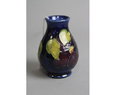 A SMALL MOORCROFT POTTERY BALUSTER VASE, 'Clematis' on blue ground, paper label to base, height approximately 10cm