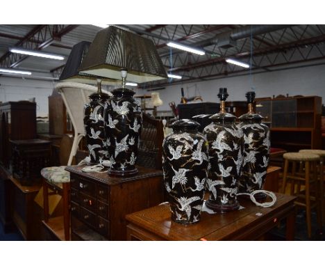 FIVE ORIENTAL CERAMIC LAMPS, and bases with crane designs over black and gold ground (one missing light fitment and wooden ba