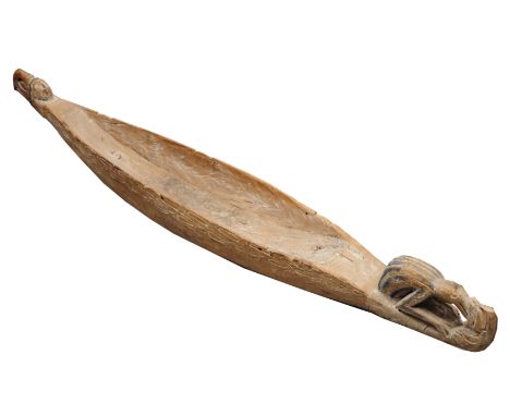 A PAPUA NEW GUINEA CARVED WOODEN FEAST BOWL in the form of a canoe with shaped prow and stylised scrolling decoration, approx